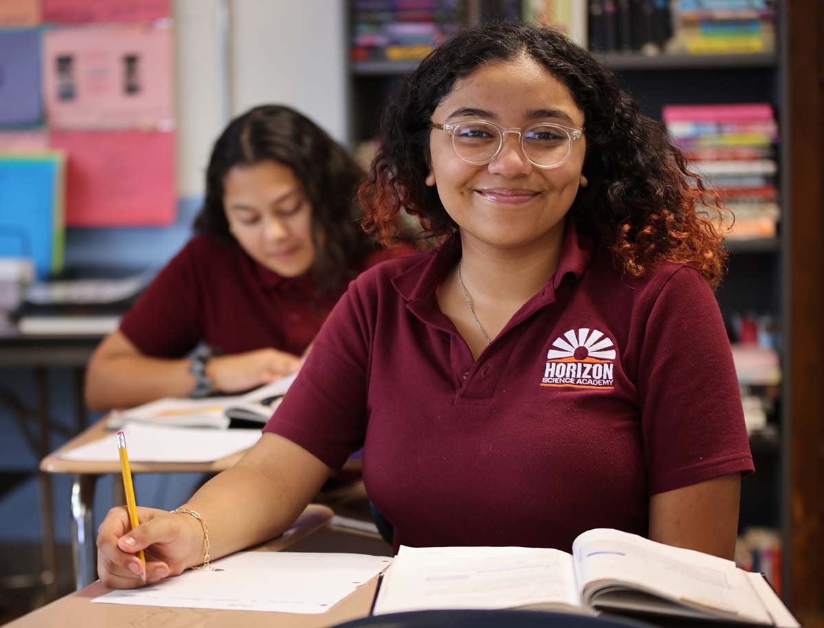 Elementary student smiling and posing together in a classroom.